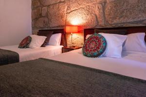 two beds in a room with a stone wall at OportoHouse in Porto