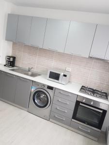 a kitchen with a washing machine and a microwave at Apartament Flo in Constanţa