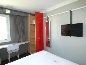 a bedroom with a bed and a tv on the wall at ibis Saintes in Saintes