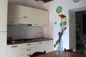 a kitchen with white cabinets and a table with a vase at Fattoria Cristina - Bilo Verde in Castelnuovo Magra