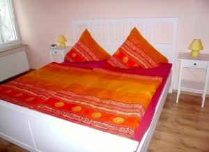 ein Bett mit roten und orangefarbenen Decken und Kissen in der Unterkunft Ferienwohnung Fam. Gansau - Insel Usedom in Zirchow