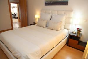 um quarto com uma grande cama branca com almofadas brancas em 20 da Vila - Apartment with Terrace em São Bartolomeu de Messines