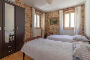 a bedroom with two beds and a brick wall at KUĆA ZA ODMOR “JADRANKA” in Zlarin