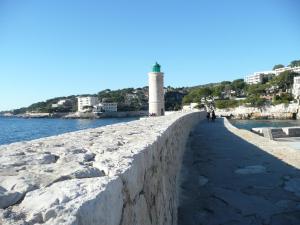 a lighthouse on a wall next to the water at le Camelia in Cassis