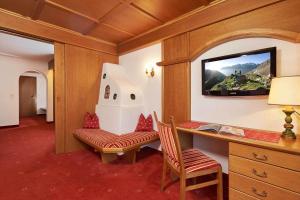 een kamer met een bureau, 2 stoelen en een televisie bij Hotel Alt Vent Tyrol in Vent