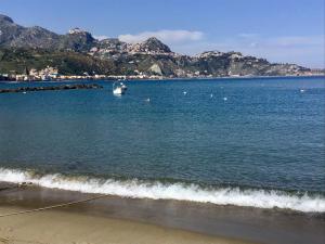 a boat in the water on a beach with mountains at Casa Patrizia in Giardini Naxos
