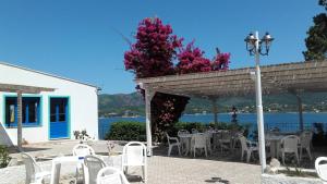 a patio with tables and chairs with a view of the water at Hotel Grotte del Paradiso in Portoferraio
