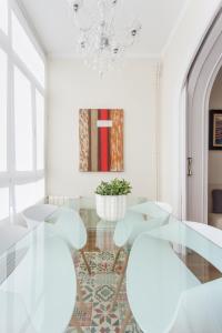 バルセロナにあるArt House Fira Apartmentsのダイニングルーム(ガラステーブル、白い椅子付)