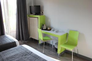 a room with a desk with two chairs and a tv at Hotel Esplanade in Strasbourg