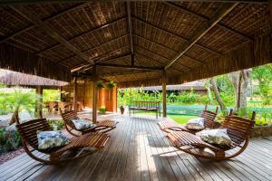a deck with chairs and a large umbrella at Tivoli Ecoresort Praia do Forte in Praia do Forte