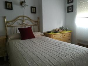 um quarto com uma cama com uma almofada vermelha e uma cómoda em Casamami em Nájera