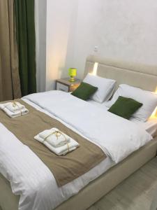 uma cama grande com lençóis brancos e almofadas verdes em Nikas Guest House em Batumi