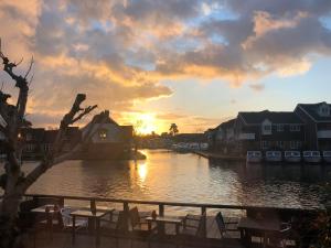 una puesta de sol sobre un río con mesas y sillas en Hotel Wroxham en Wroxham