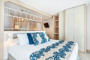 a bedroom with a large bed with blue and white pillows at Eurostars Ibiza in Ibiza Town