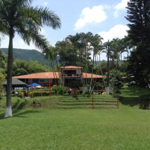 une maison avec des palmiers dans un parc dans l'établissement Finca El Sueño De Mi Abuelo, à Pereira