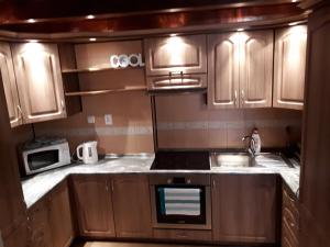 a kitchen with wooden cabinets and a sink and a microwave at Apartmán Bianka in Rabča