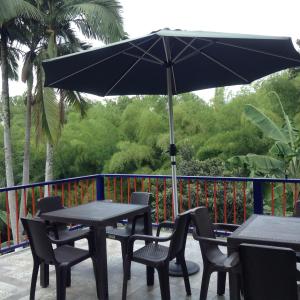 a table and chairs with an umbrella on a balcony at Finca El Sueño De Mi Abuelo in Pereira