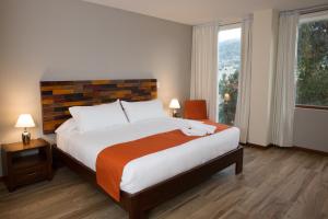 Ilalo Garden Hotel & Restaurant في كيتو: غرفة نوم بسرير كبير ونافذة كبيرة
