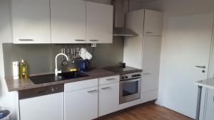 a kitchen with white cabinets and a sink and a stove at Zimmervermietung Seefeld in Lingen