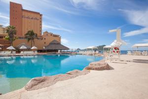 a large swimming pool with a hotel in the background at Costa de Oro Beach Hotel in Mazatl&aacute;n