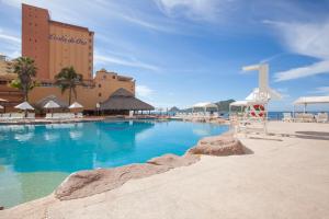 a large swimming pool with a hotel in the background at Costa de Oro Beach Hotel in Mazatlán