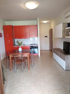 une cuisine avec des placards rouges, une table et des chaises dans l'établissement Matera Da - Mare, à Marina di Pisticci