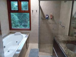 La salle de bains est pourvue d'une baignoire, d'une douche et d'un lavabo. dans l'établissement Linda casa na Serra da Cantareira, à Mairiporã