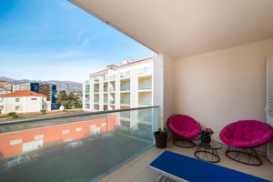 einen Balkon mit rosa Stühlen und Stadtblick in der Unterkunft Dubrovnik Style Luxury apartment 2 in Dubrovnik