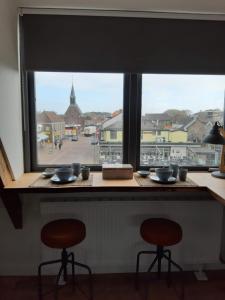 a window with two stools and a view of a town at Room at the Beach Egmond in Egmond aan Zee