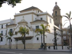 un gran edificio blanco con palmeras delante en Casa Plotina Pompeya en Cádiz