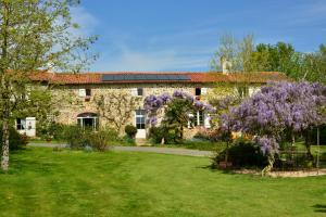 een groot stenen huis met paarse bloemen in de tuin bij La Frapperie in La Pommeraie-sur-Sèvre
