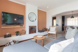 een woonkamer met een bank en een tv bij Seascape Cottage in Kaapstad