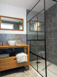 ein Bad mit einem Waschbecken und einer Glasdusche in der Unterkunft Chambres d'hôtes Quatre Mains in Saint-Priest-des-Champs