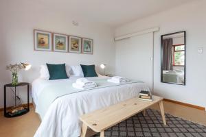 een slaapkamer met een groot wit bed en een houten tafel bij Seascape Cottage in Kaapstad