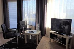 Helles 1-Zimmer-Apartment in Hemmingen/Hannover في هيمنغن: غرفة معيشة فيها كراسي وتلفزيون وطاولة