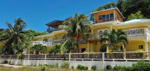 una casa amarilla con palmeras delante en The Islander's Inn en Union Island