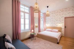 a bedroom with two beds and a couch and windows at " Mademoiselle " 17 Boulevard du Champ de Mars in Colmar