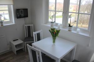 a white table with a vase of flowers on it at Stuga på Hammarbergs Gård in Kungsbacka