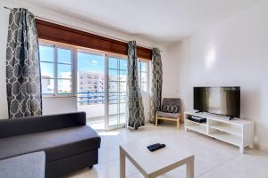 un salon avec un canapé et une télévision dans l'établissement Rei - Quarteira - 3 min to the beach, à Quarteira