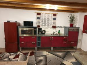 una cucina con armadi rossi e forno a microonde di Martin´s Ferienwohnung a Furth im Wald