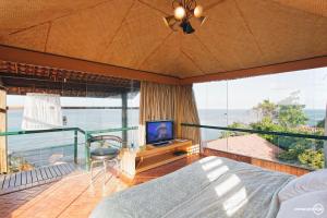 Dormitorio con balcón con cama y TV en Pousada do Alto, en Japaratinga