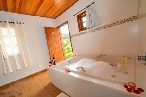 ein großes Bad mit einer Badewanne und einem Fenster in der Unterkunft Chalés Leopoldo em Monte Verde in Monte Verde