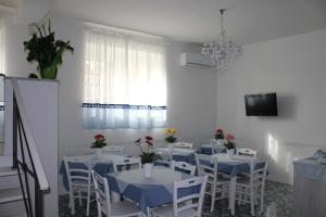 a dining room with white tables and chairs and a chandelier at IL GIARDINO DEI GLICINI in Ercolano