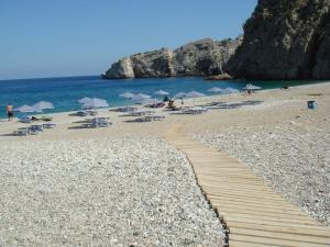 a pathway on a beach with chairs and umbrellas at Aperi View in Karpathos