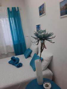 a room with a bed with a vase with a plant on it at Fedra in Novi Sad