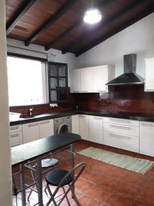 a kitchen with white cabinets and a table with chairs at Monte frio de Tenerife in La Guancha