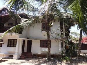 una casa blanca con una palmera delante de ella en Montecello, en Trivandrum
