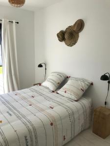 een witte slaapkamer met een bed met 2 kussens bij Ker Nany in Sainte-Marine