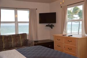 a hotel room with a bed and a tv and windows at La Terrace Oceanfront in Hollywood