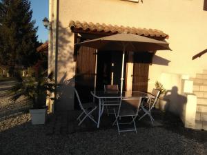 a table and chairs under an umbrella outside a house at patrice et chrstel Appartement indépendant in Les Malossannes